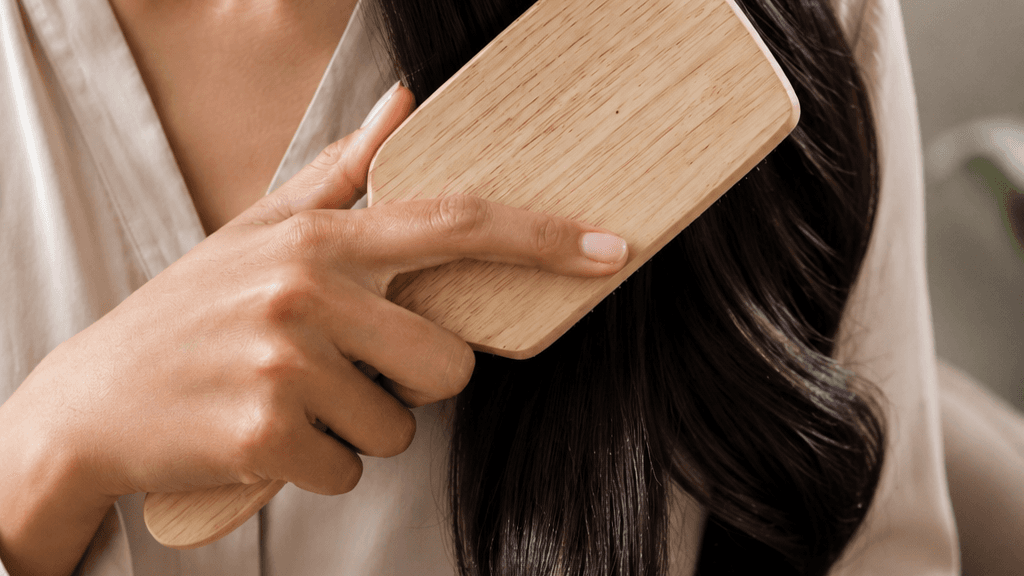 Donna che pettina i capelli lunghi con una spazzola in legno